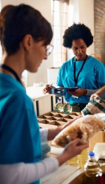 Diverse group of people sorting donated food for those in need while working at community center,